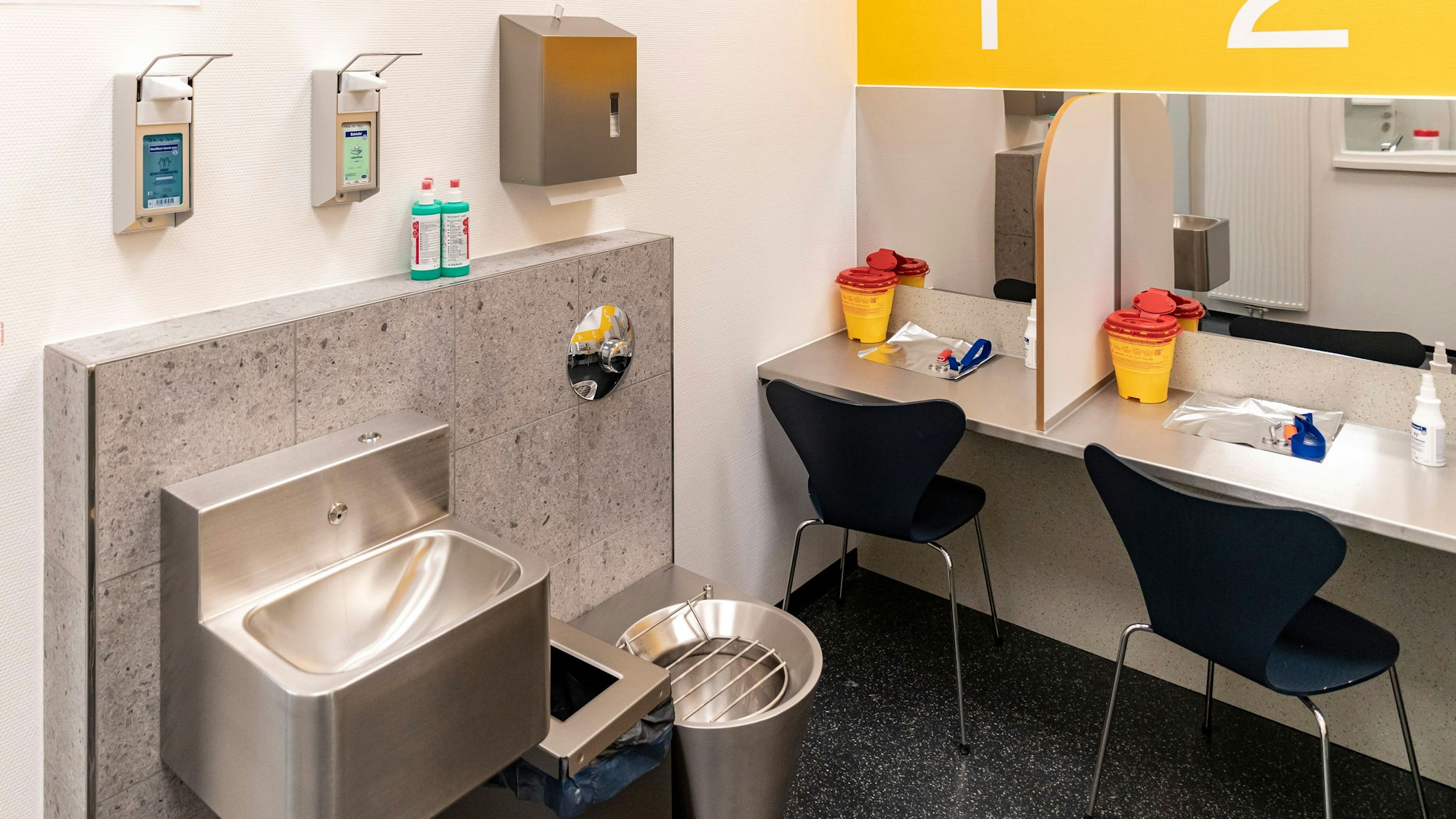 Das Bild zeigt einen Spiegel, zwei Stühle und ein Waschbecken.