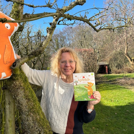 Ein aufblasbarer Apfelbär sitzt im Apfelbaum, Annette Langen mit ihrem Buch