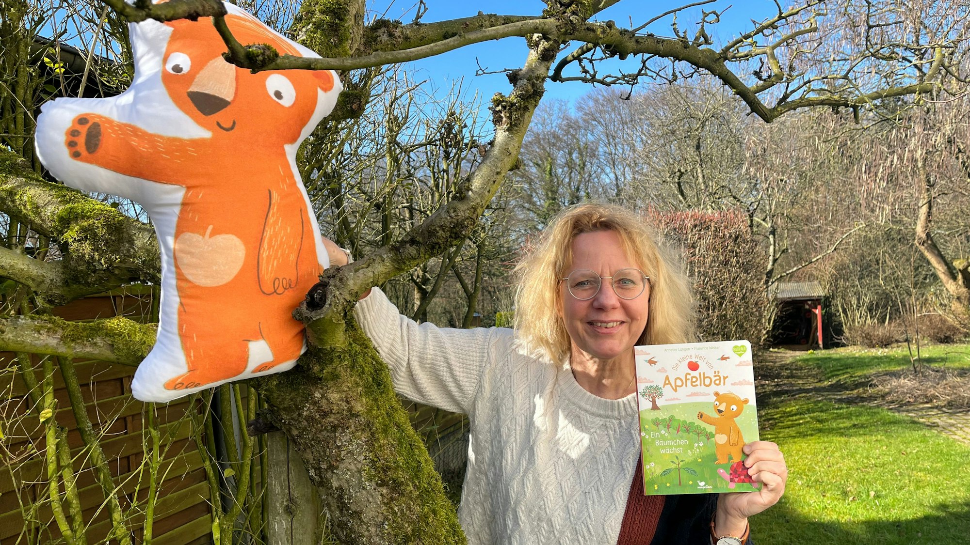 Ein aufblasbarer Apfelbär sitzt im Apfelbaum, Annette Langen mit ihrem Buch