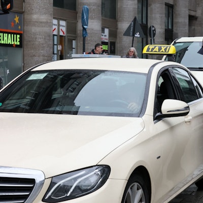 Zöllner sprechen mit einem Taxifahrer, der im Auto sitzt.