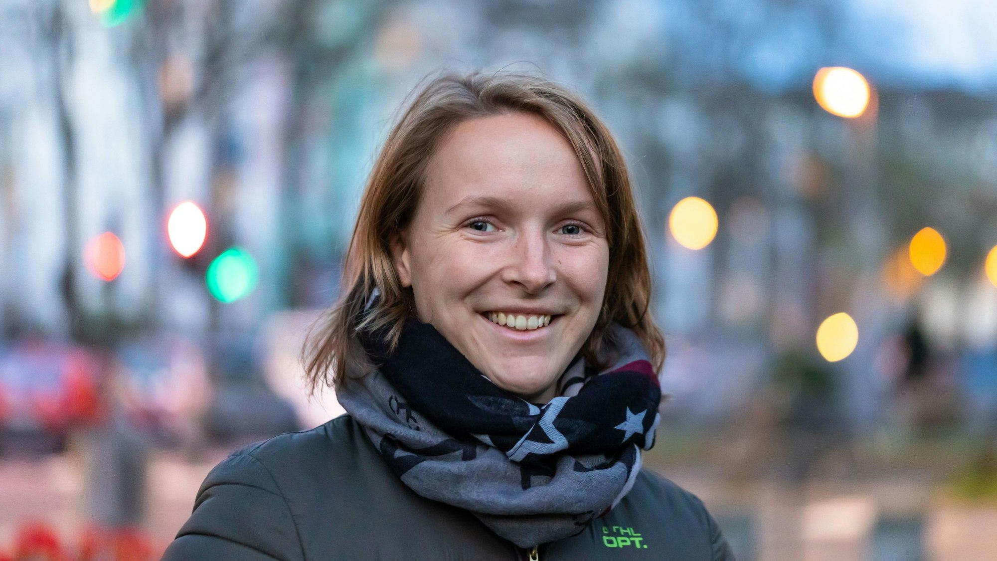 Annika Holzke trägt einen grau-schwarzen Schal und lacht in die Kamera.