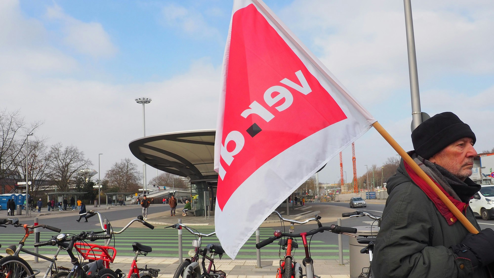 Ein Mann hält am Busbahnhof in Wiesdorf eine Verdi-Fahne.