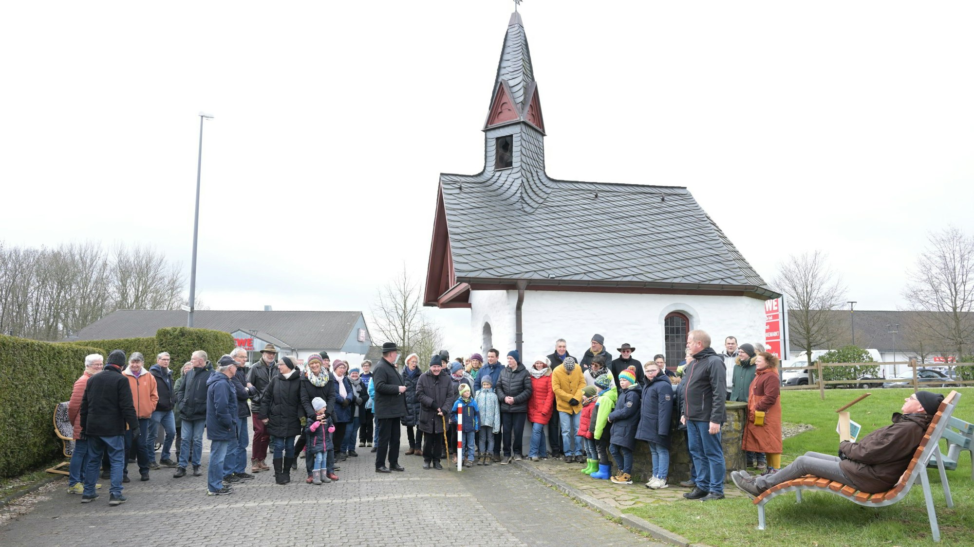 Menschen stehen bei der Eröffnung des Schöpfungswanderweg in Bechen vor einer Kirche.