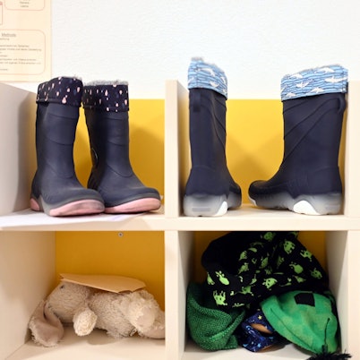 Kinderstiefel, ein Stofftier und Kinderkleidung sind in einem Regal untergebracht.