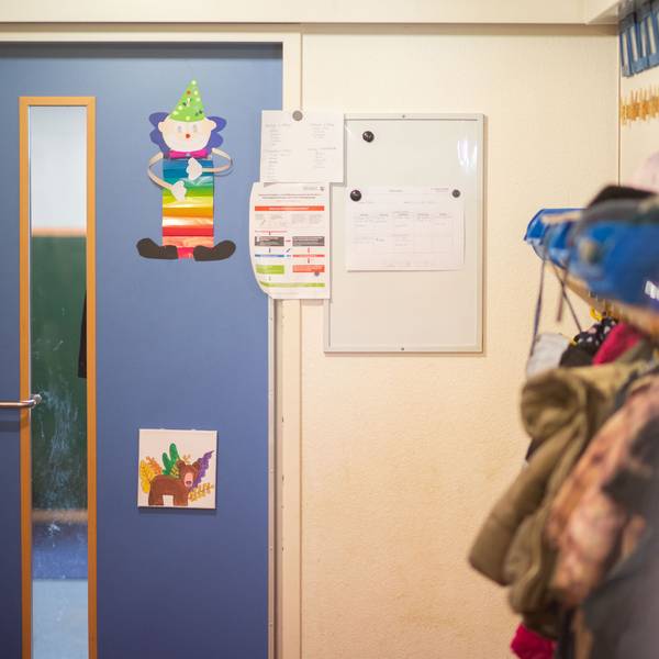Kindergarten im Kreis Euskirchen. Tür mit Bildern, am rechten Rand hängen Jacken und Rucksäcke.