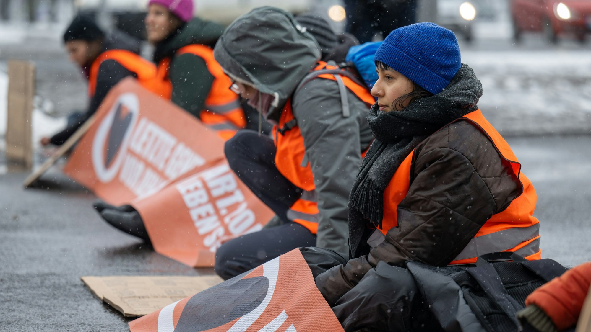 08.03.2023, Sachsen, Leipzig: Aktivistinnen der Letzten Generation haben sich auf der Fahrbahn der Jahnallee in Leipzig festgeklebt. Mit Bannern und Plakaten haben die Aktivistinnen den Verkehr in Fahrtrichtung Innenstadt aufgehalten.