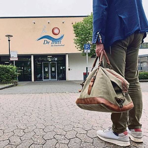 Das Foto zeigt einen Mann mit einer Sporttasche, der in Richtung des Familienbads De Bütt geht.