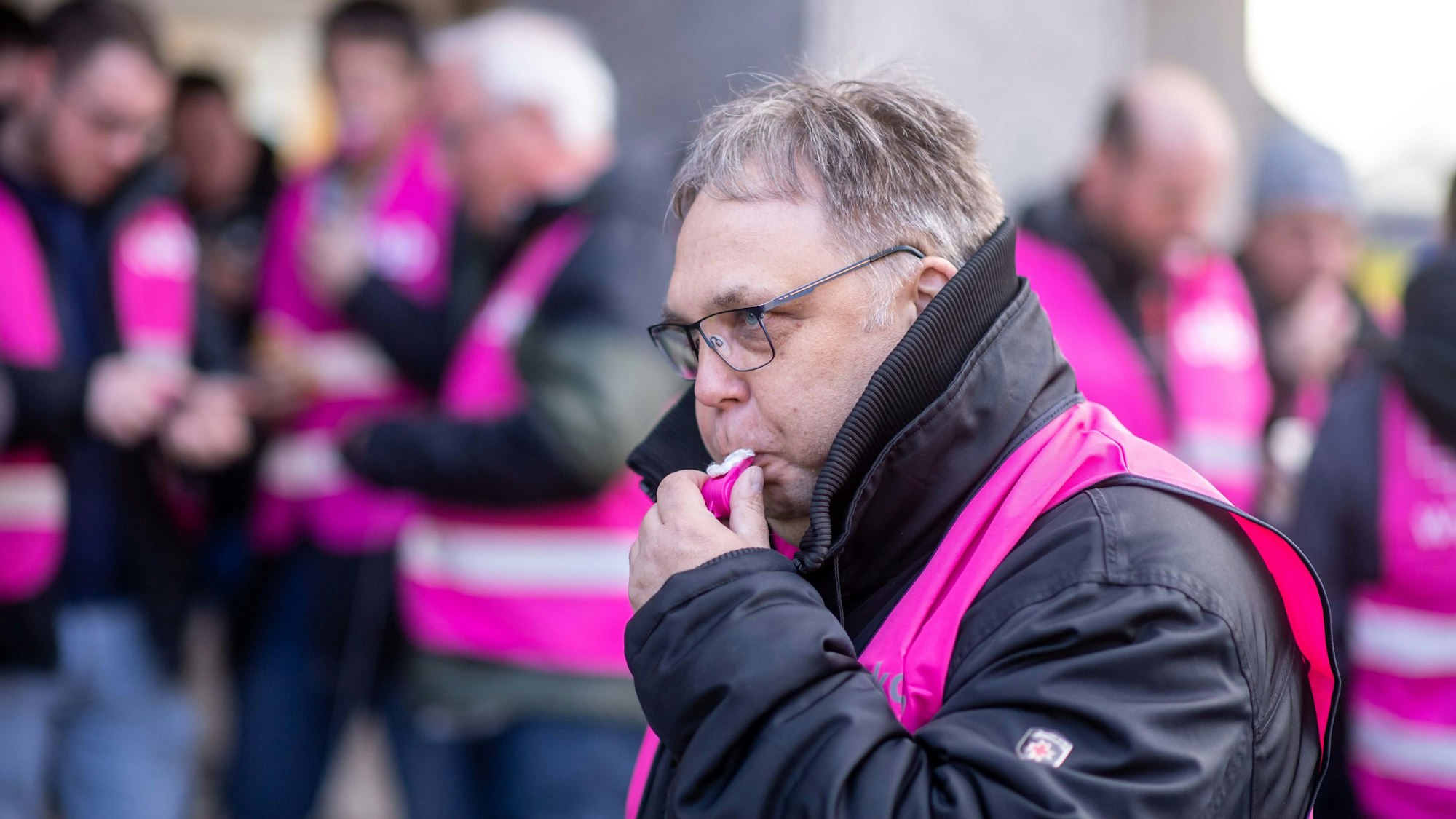 Ein streikender Mitarbeiter bläst vor dem Euskirchener Rathaus in eine Trillerpfeife.