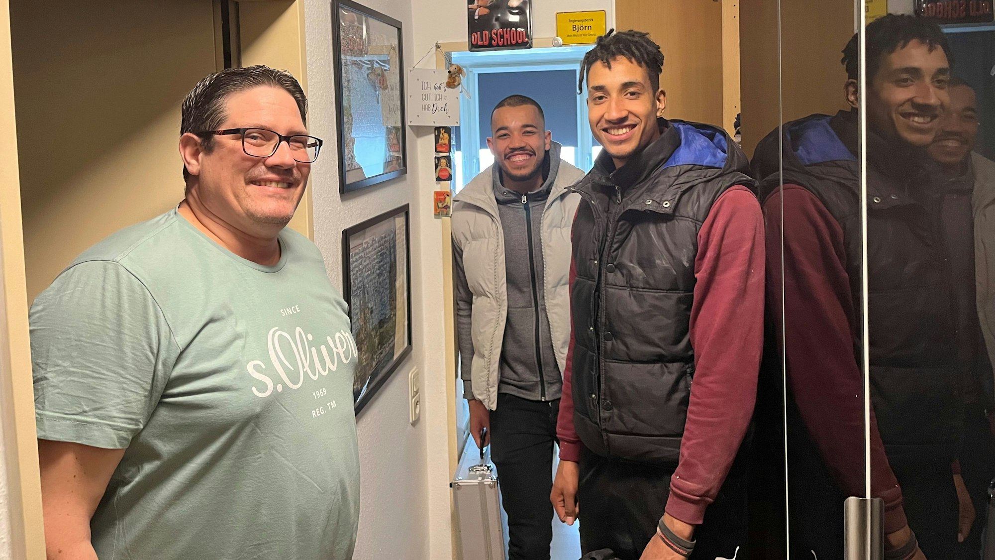 Drei Männer stehen im Flur.