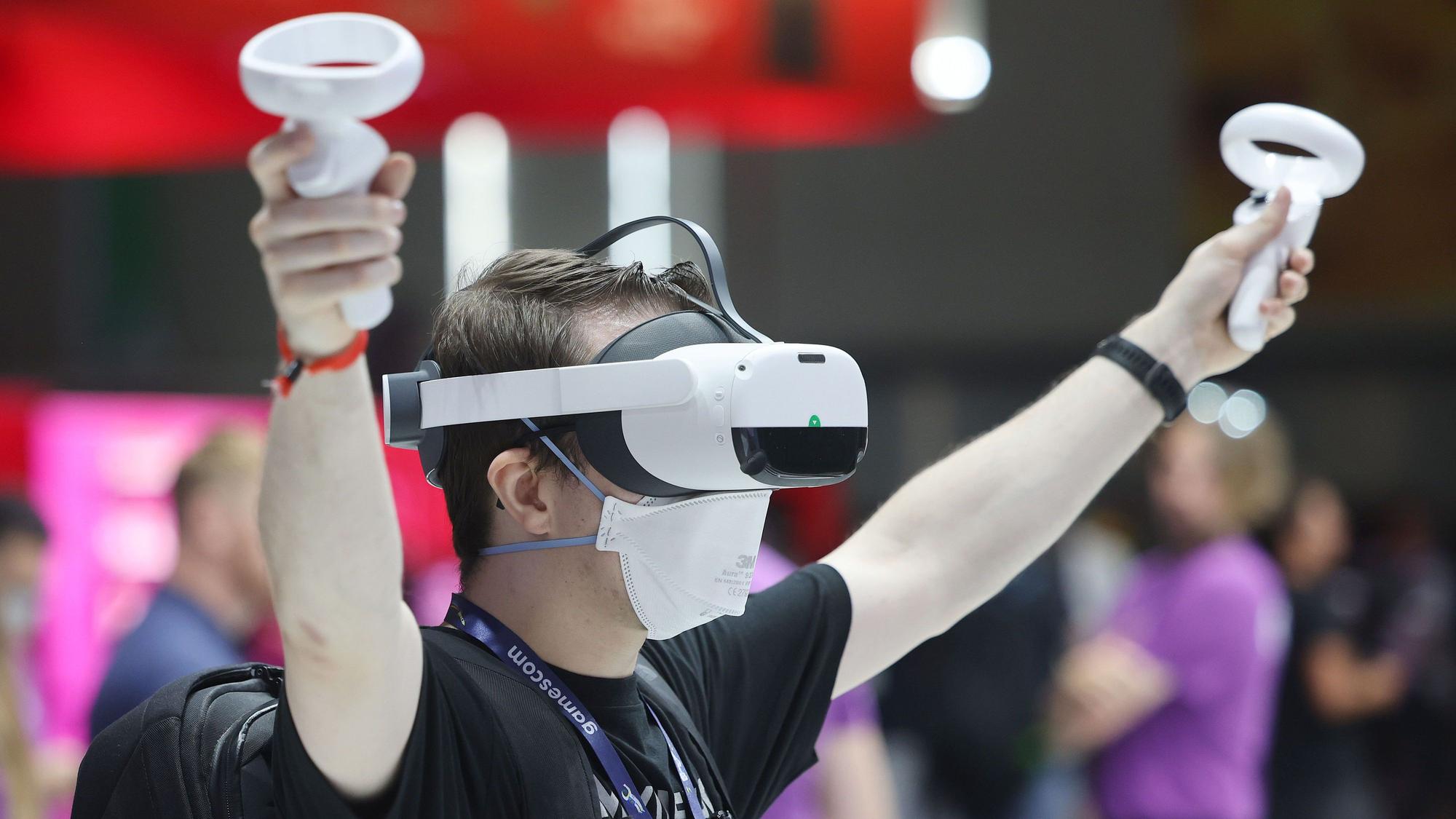Gamescom 2022: Ein Messebesucher testet mit einer VR Brille (Virtual Reality) ein Computerspiel.