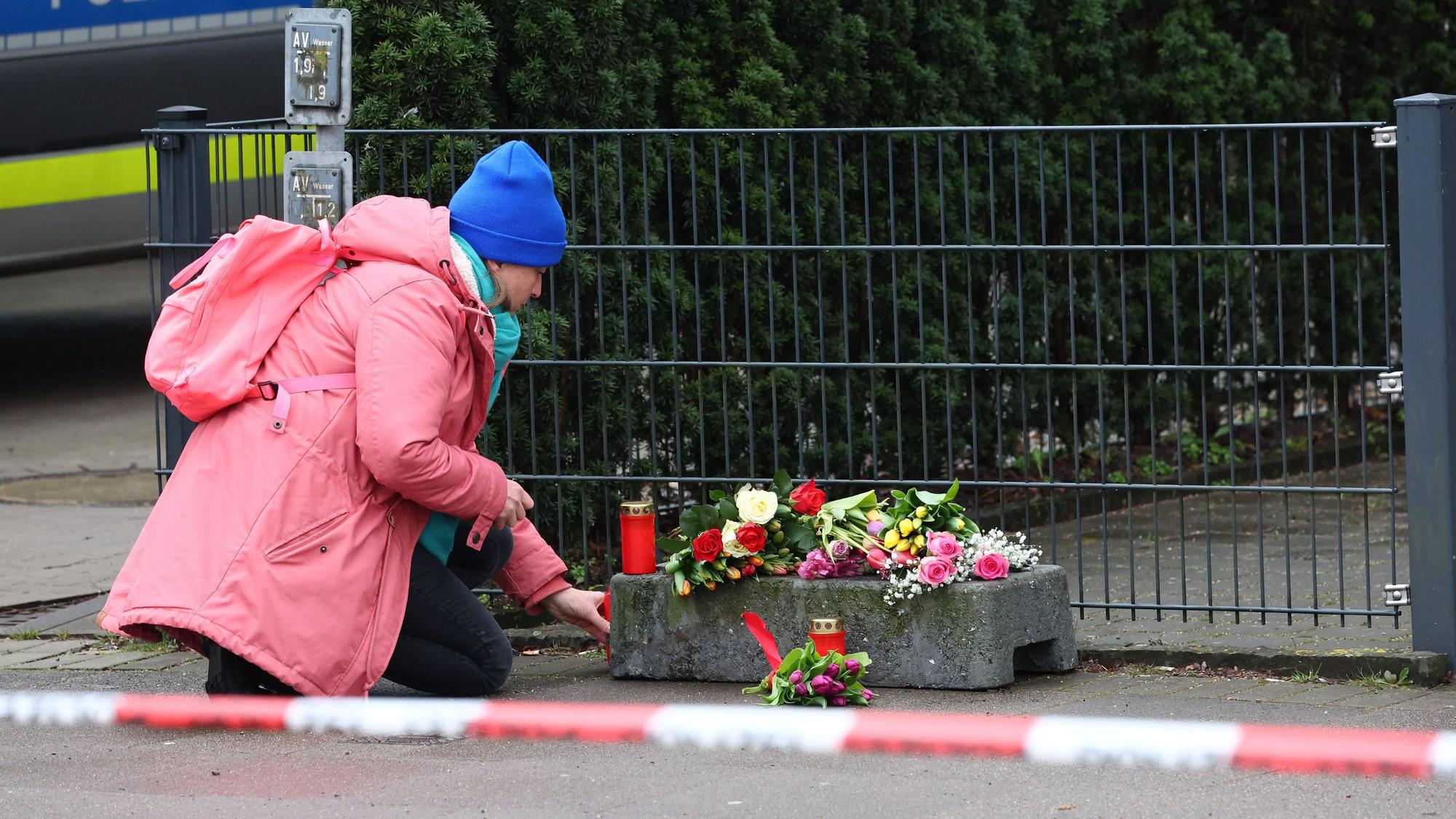 Eine Frau legt vor dem Gebäude der Zeugen Jehovas im Stadtteil Alsterdorf Blumen nieder.