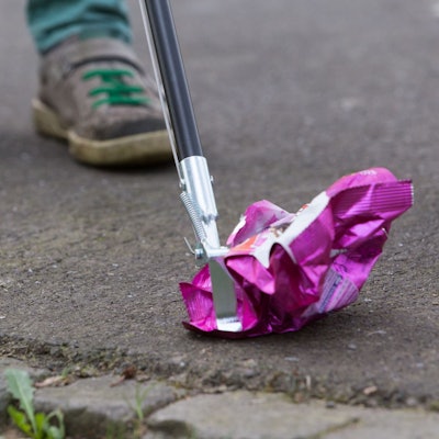 Müll wird mit einer Müllgreifzange vom Boden aufgehoben.