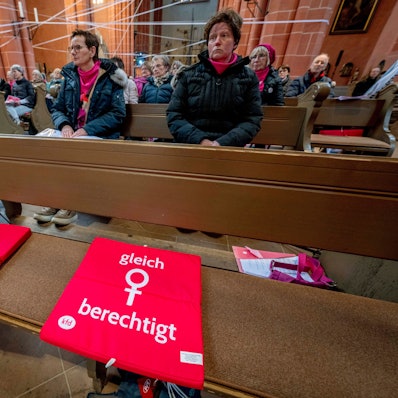 Ein rotes Sitzkissen auf einer Bank im Frankfurter Dom mit der Aufschrift „gleich berechtigt“ und dem Frauen-Symbol weist auf die Forderung des kirchlichen Reformprozesses „Synodaler Weg“ hin, die Weiheämter in der katholischen Kirche für Frauen zu öffnen.
