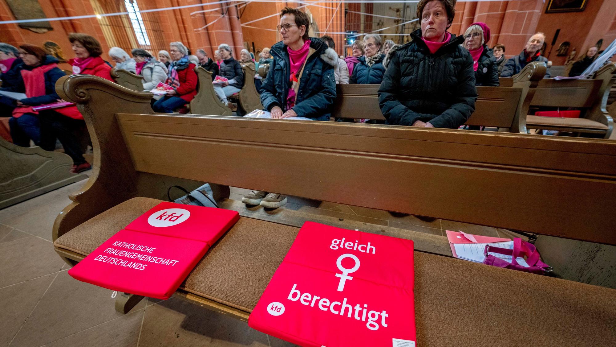 Ein rotes Sitzkissen auf einer Bank im Frankfurter Dom mit der Aufschrift „gleich berechtigt“ und dem Frauen-Symbol weist auf die Forderung des kirchlichen Reformprozesses „Synodaler Weg“ hin, die Weiheämter in der katholischen Kirche für Frauen zu öffnen.