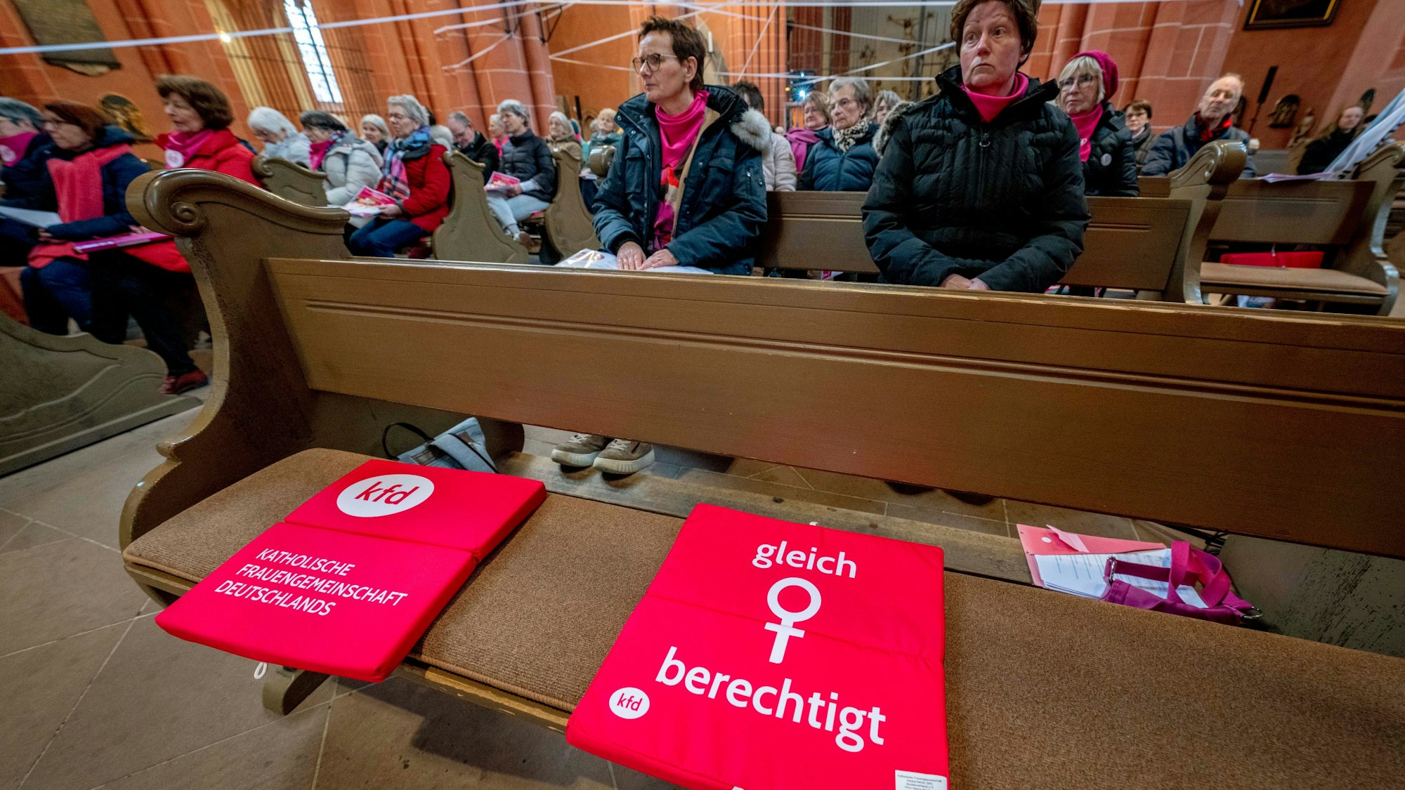 Ein rotes Sitzkissen auf einer Bank im Frankfurter Dom mit der Aufschrift „gleich berechtigt“ und dem Frauen-Symbol weist auf die Forderung des kirchlichen Reformprozesses „Synodaler Weg“ hin, die Weiheämter in der katholischen Kirche für Frauen zu öffnen.