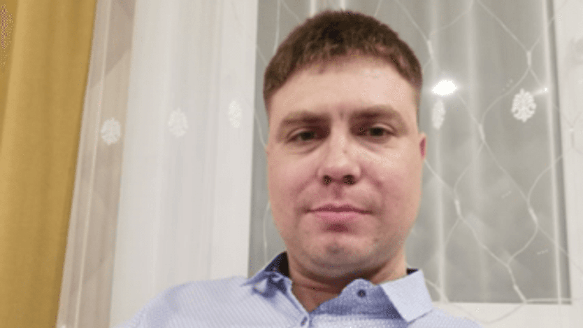 Igor Garshin sitzt auf einem Sofa und blickt in die Kamera. Er trägt ein Hemd.