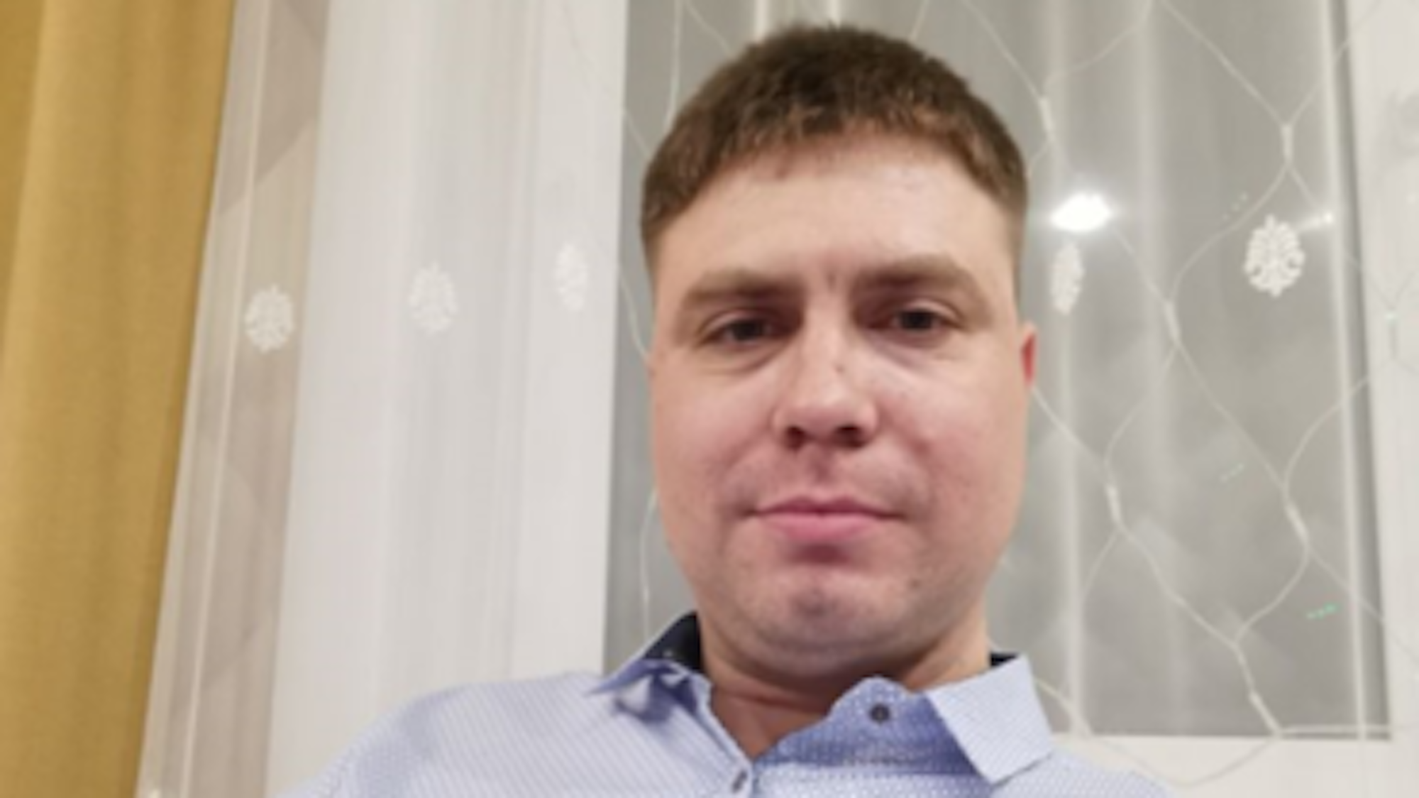 Igor Garshin sitzt auf einem Sofa und blickt in die Kamera. Er trägt ein Hemd.