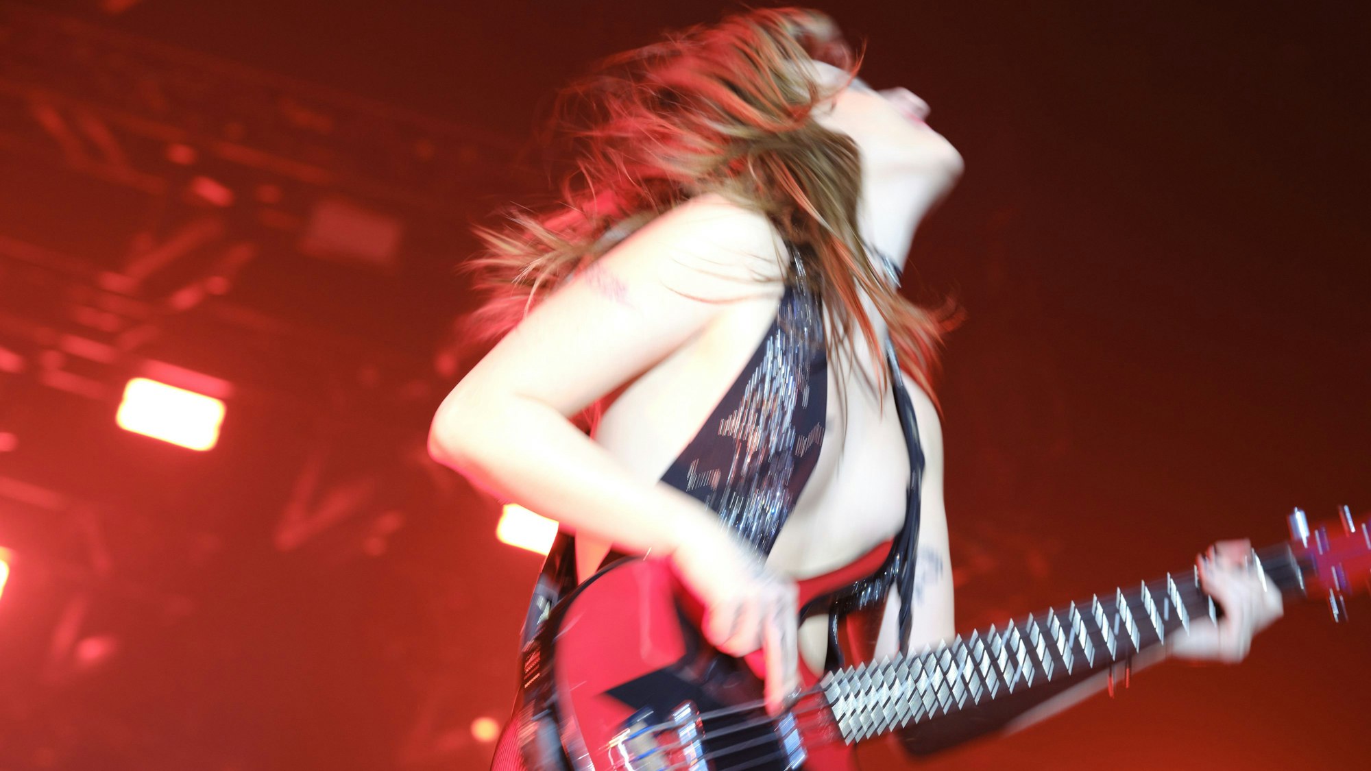 Bassisitin Victoria De Angelis spielt Bass und wirft dabei ihren Kopf nach hinten, sodass ihr Haare wild herumwirbeln.