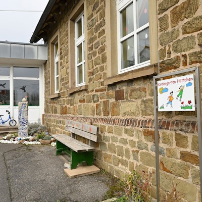 Kindergarten Odenthal-Hüttchen, Altbau mit Anbau, davor eine Sitzbank.