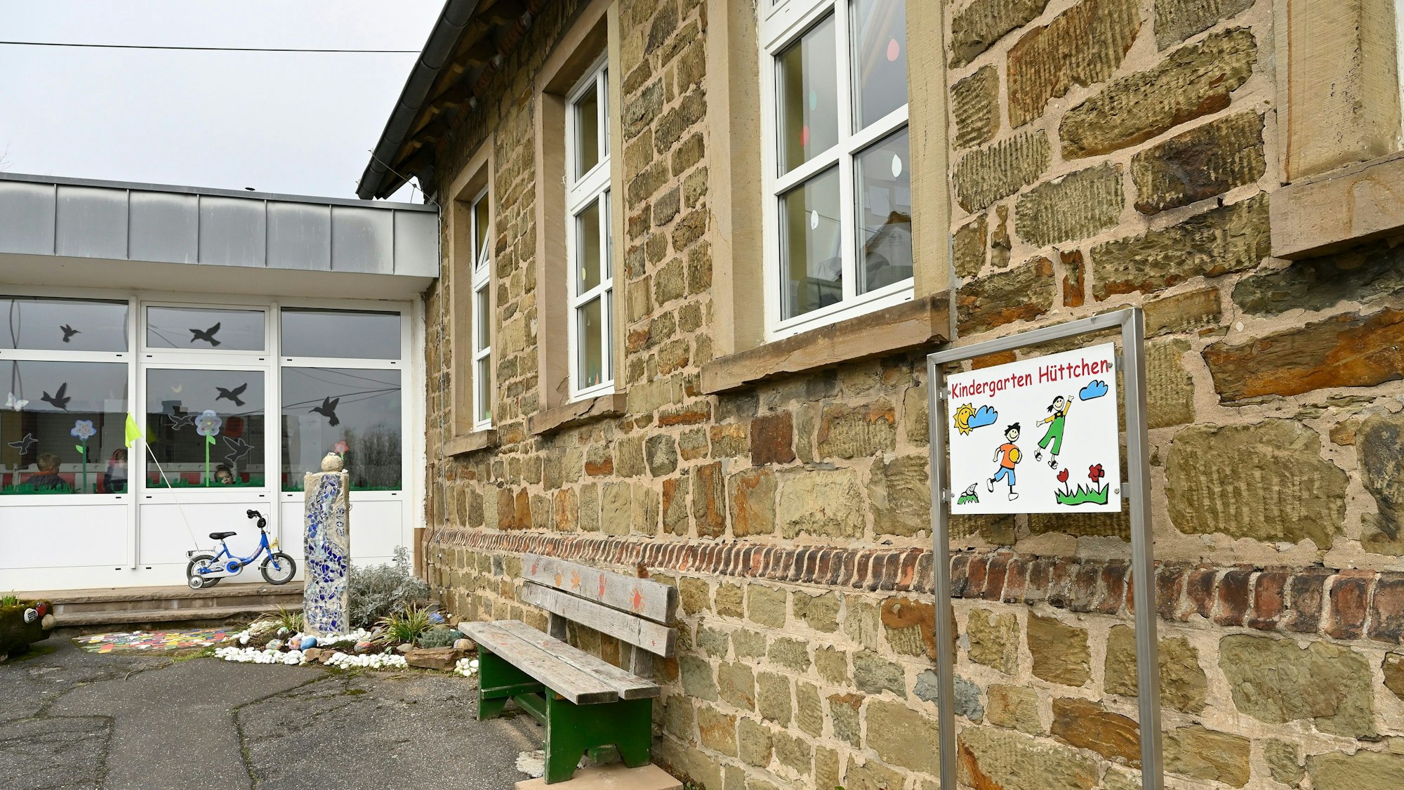 Das Gebäude des Kindergarten St. Mariä Himmelfahrt in Odenthal-Hüttchen. Davor eine Holzbank.