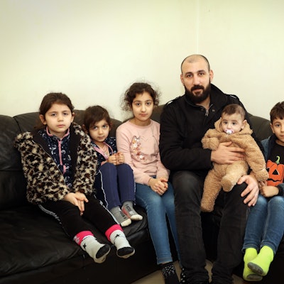 Saad, syrischer Familienvater, und seine fünf Kinder sitzen auf einem Sofa.