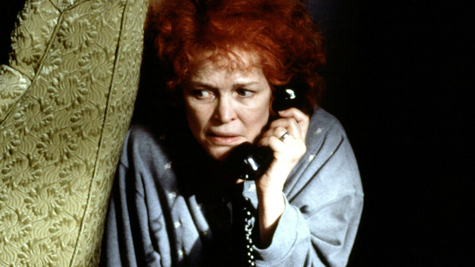 Ellen Burstyn mit Telefon hinter einem Sessel.