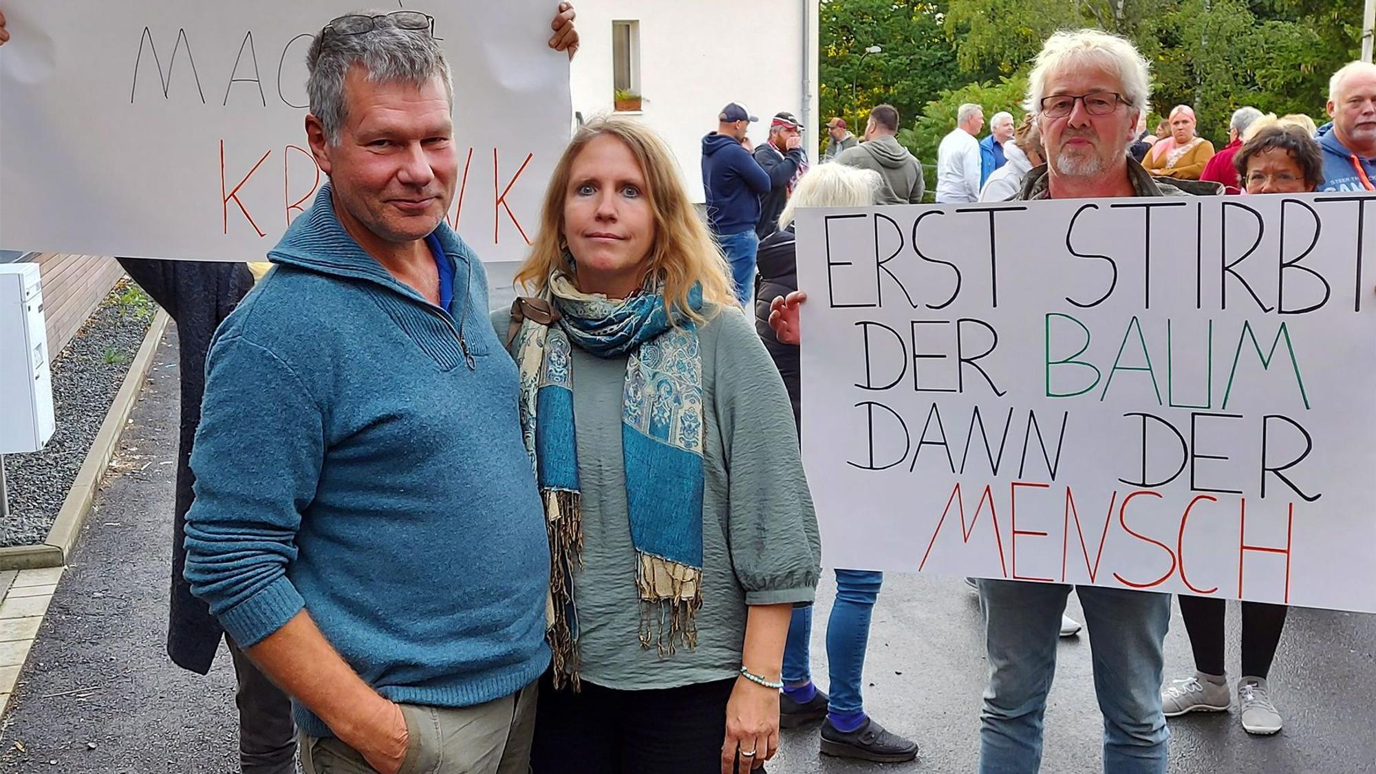 Einige Menschen protestieren mit Plakaten gegen den Bau eines Feriendorfs am Freilinger See.