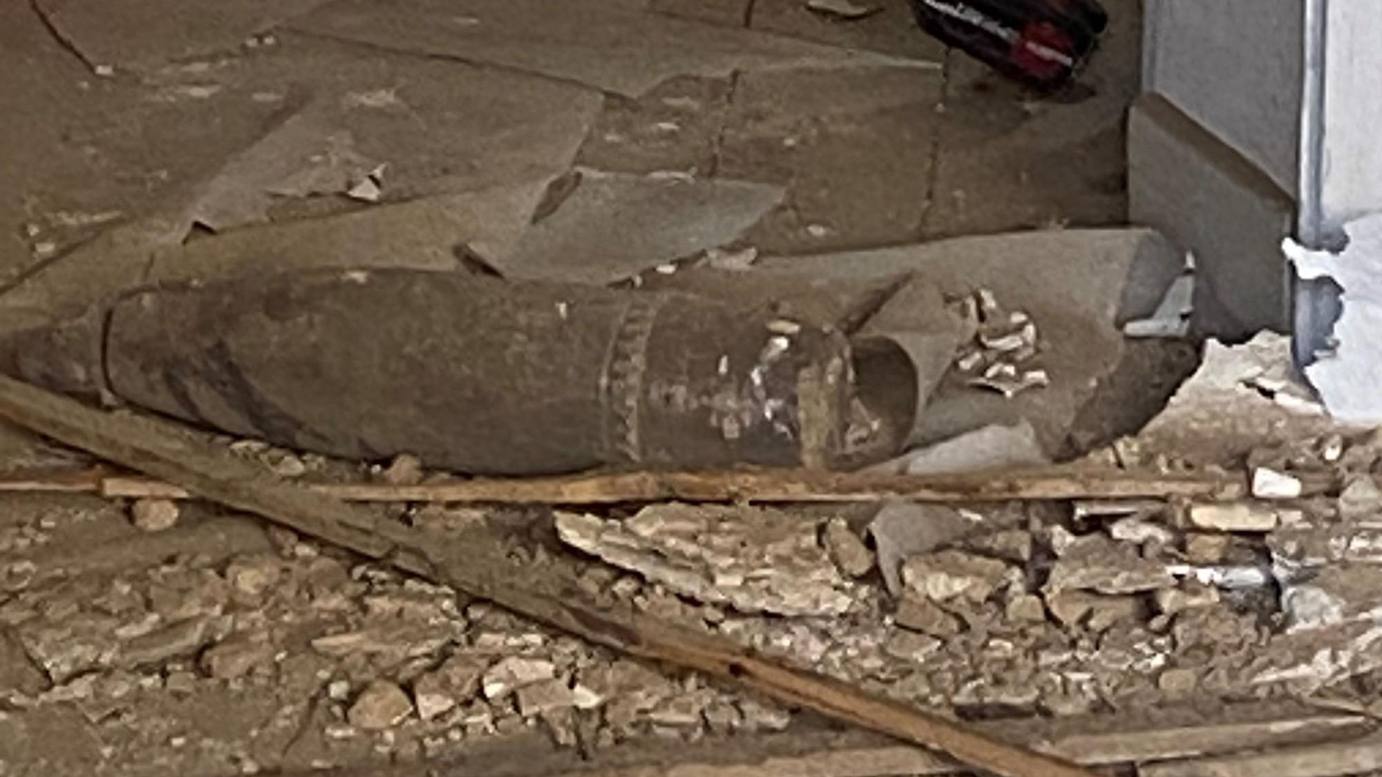 Zwischen Bauschutt und Holzleisten liegt eine lange, zylinderförmige Bombe.