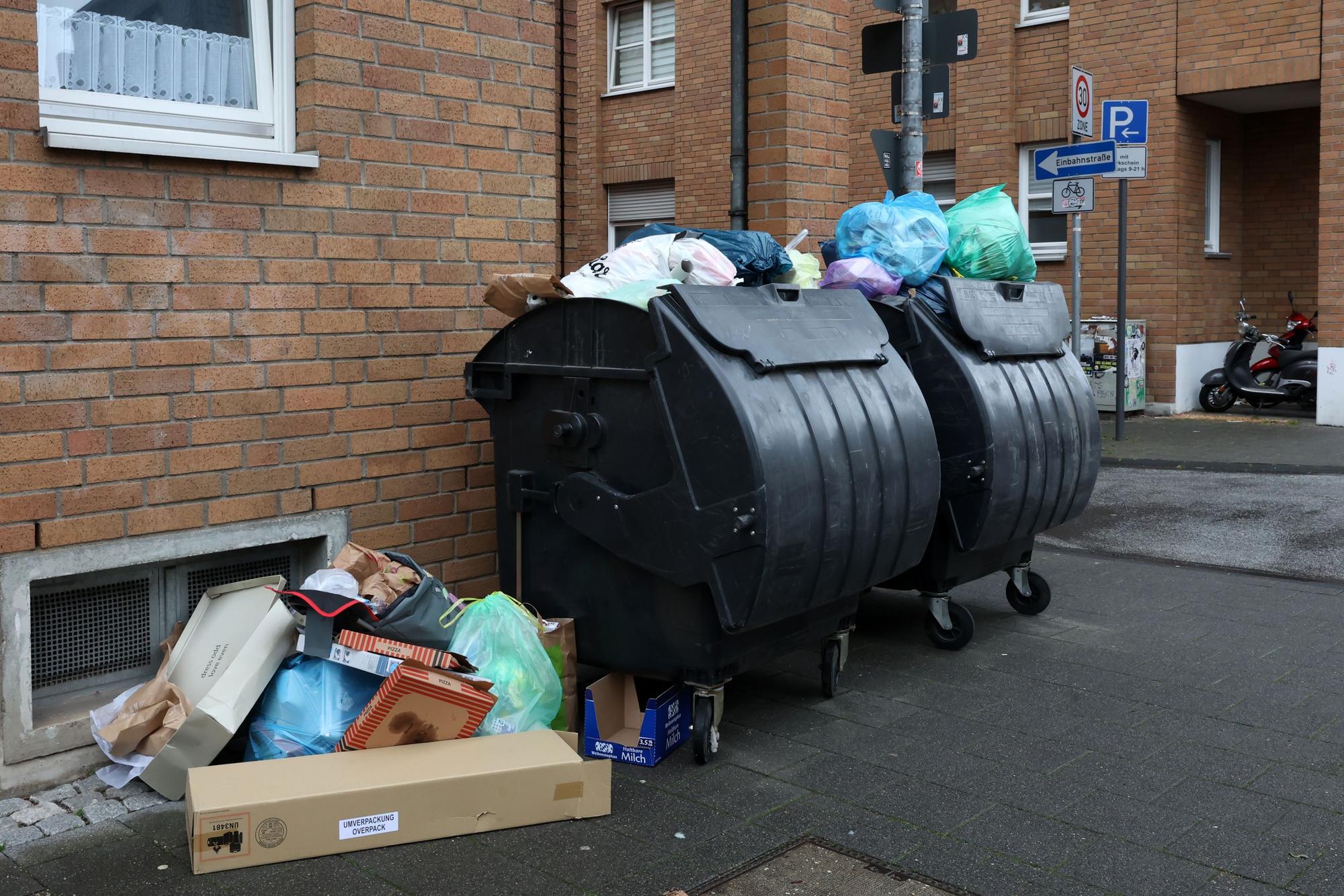 Ungeleerte Mülltonnen und Müllreste in der Stadt.
