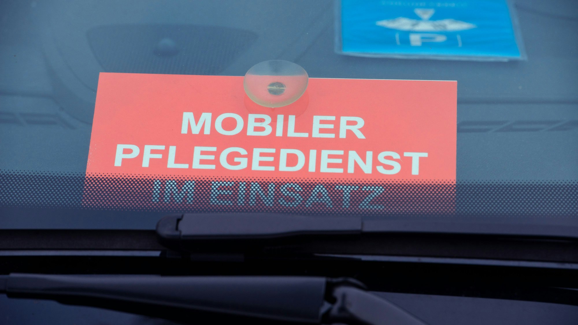 Ein Schild mit dem Schriftzug «Mobiler Pflegedienst im Einsatz» liegt in einer Windschutzscheibe.