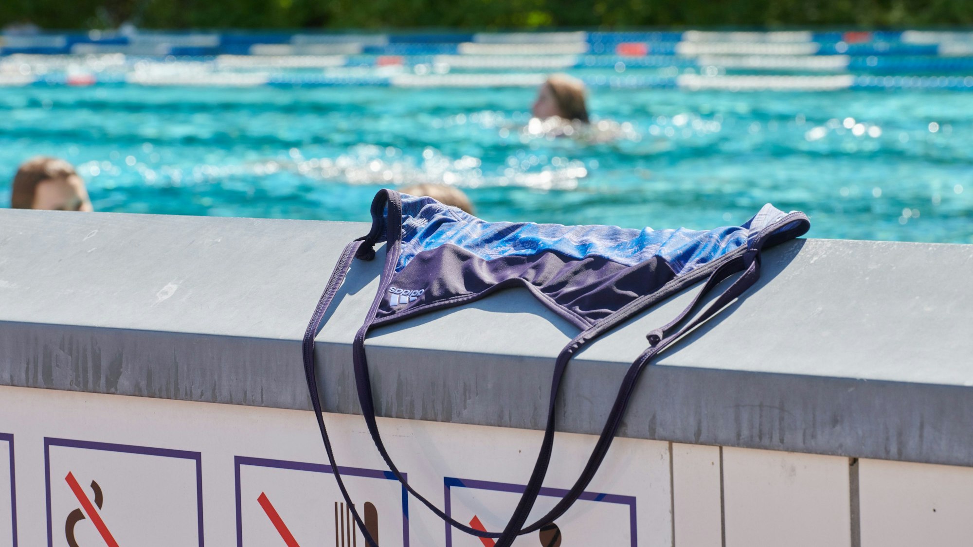 Ein Bikinioberteil auf dem Rand eines Schwimmbeckens.