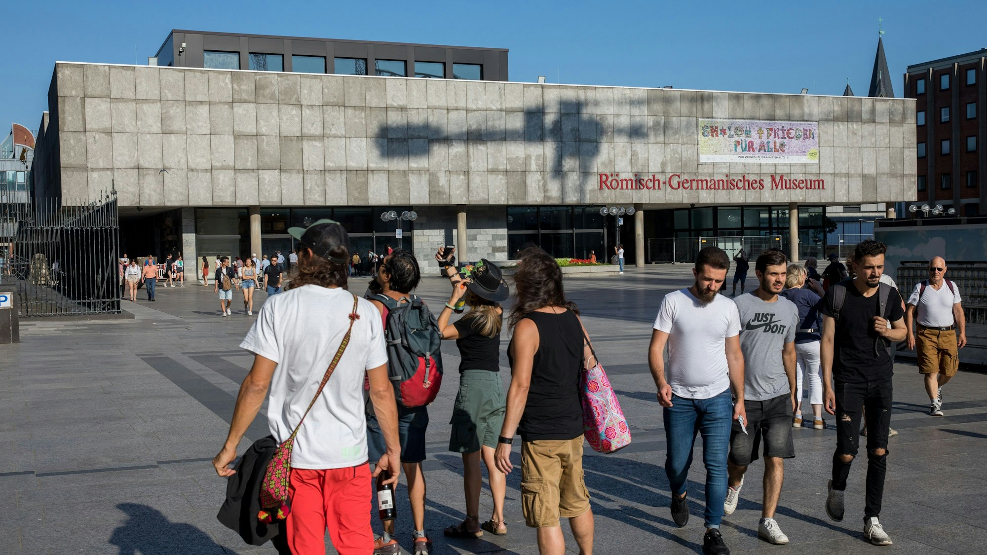 Das Bild zeigt das Römisch-Germanische Museum mit fotografierenden Touristen im Vordergrund
