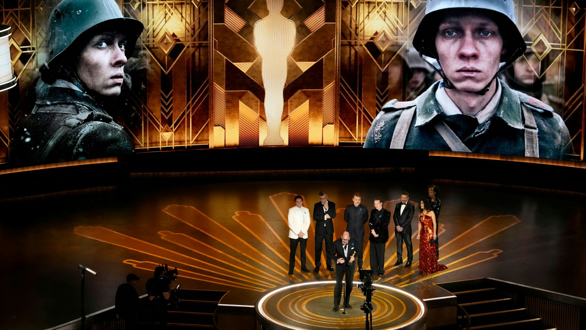 Regisseur Edward Berger (vorne) nimmt den Preis für «Im Westen nichts Neues» aus Deutschland für den besten internationalen Spielfilm bei der Oscar-Vverleihung im Dolby Theatre in Los Angeles entgegen. Hinten stehen Daniel Brühl (l-r), Malte Grunert, Albrecht Schuch, Felix Kammerer, Antonio Banderas und Salma Hayek.