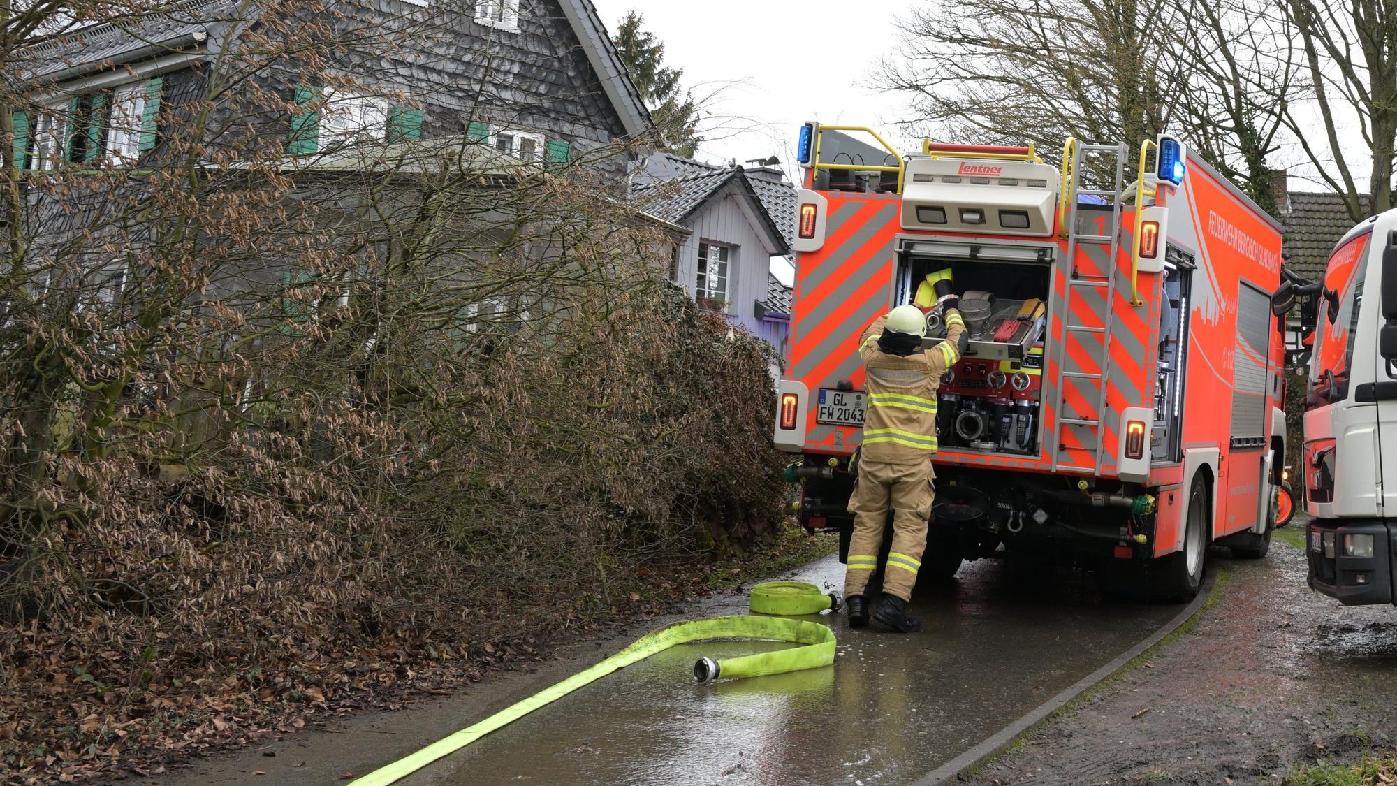Ein Feuerwehrmann lädt Material in ein Feuerwehrfahrzeug. Im Hintergrund sind mehrere Gebäude zu sehen.