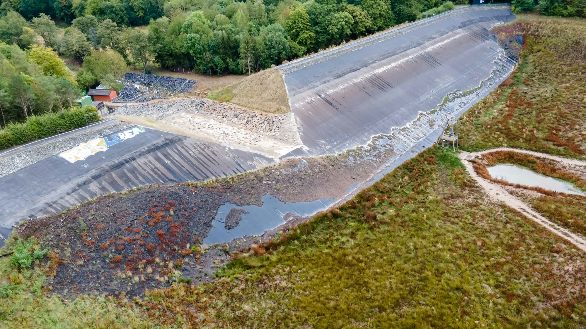 Die Luftaufnahme zeigt den Damm der Steinbachtalsperre bei Kirchheim. In der Mitte ist eine große Scharte zu sehen.