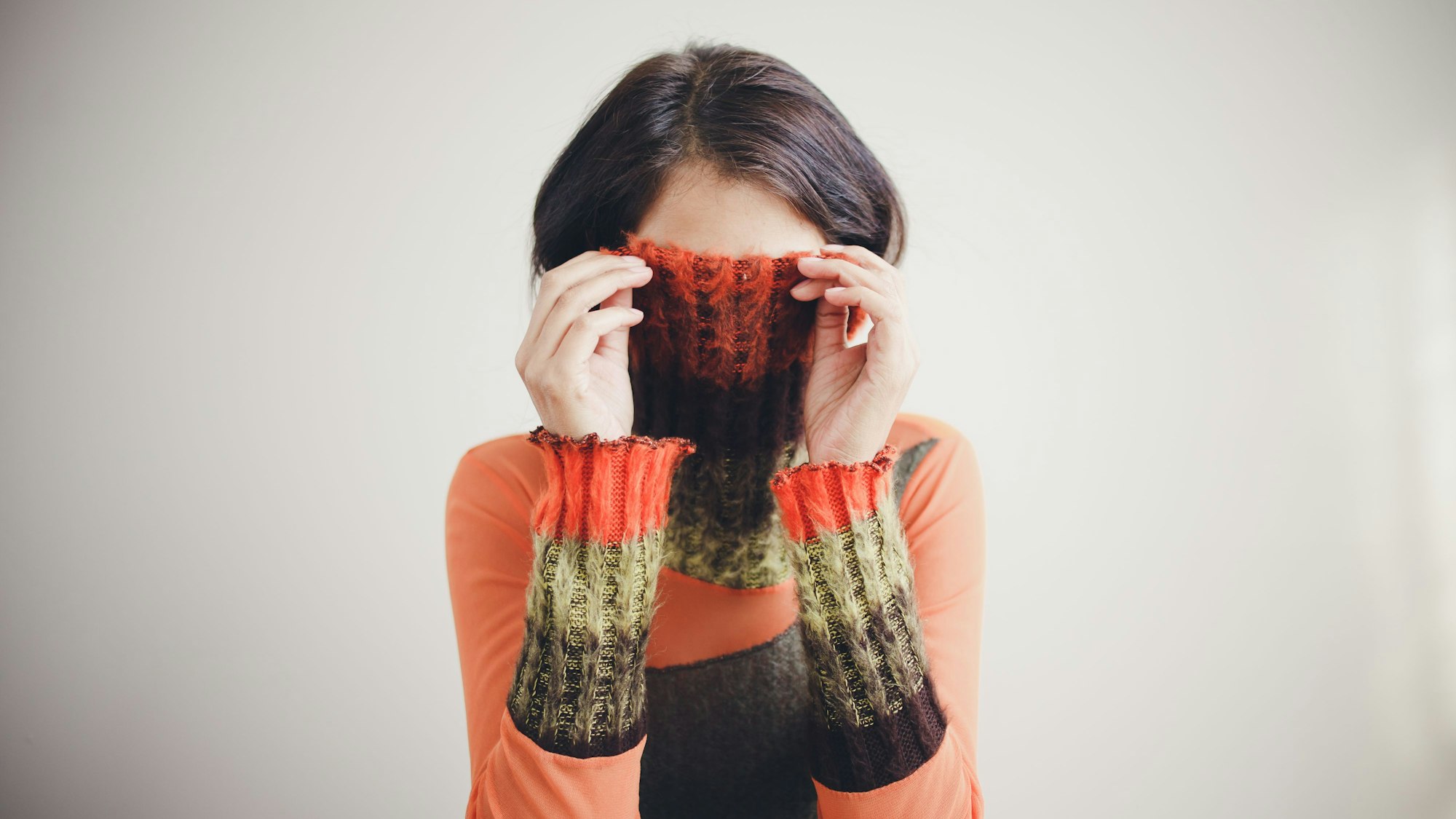 Frau versteckt ihr Gesicht in ihrem Pullover