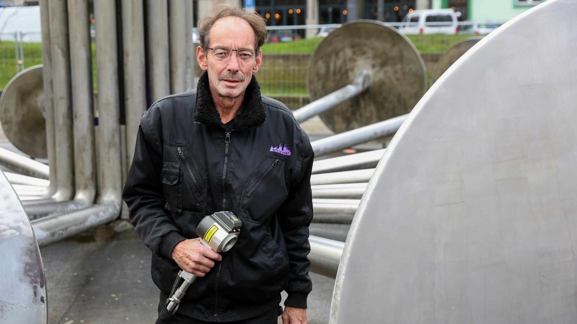 Olaf Zaller stet vor dem Brunnen auf dem Ebertplatz und hält den Laser in seiner Hand.