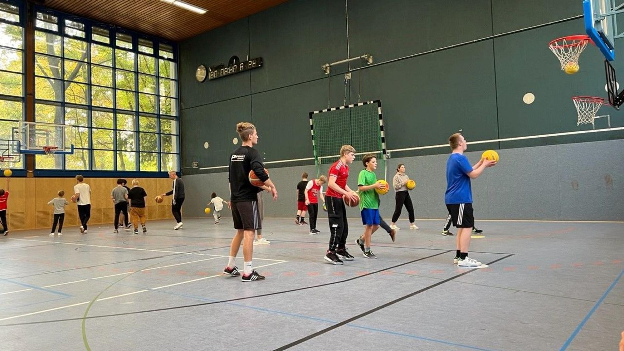 Basketballtraining bei der „Bananenflanke“ in einer Halle der Deutschen Sporthochschule Köln: Viele Kinder sind zu sehen, die mit gelben Bällen Basketball trainieren.