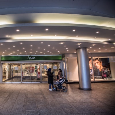 Zwei Frauen stehen mit einem Kinderwagen vor der geschlossenen Tür des Galeria-Warenhauses in Leverkusen.