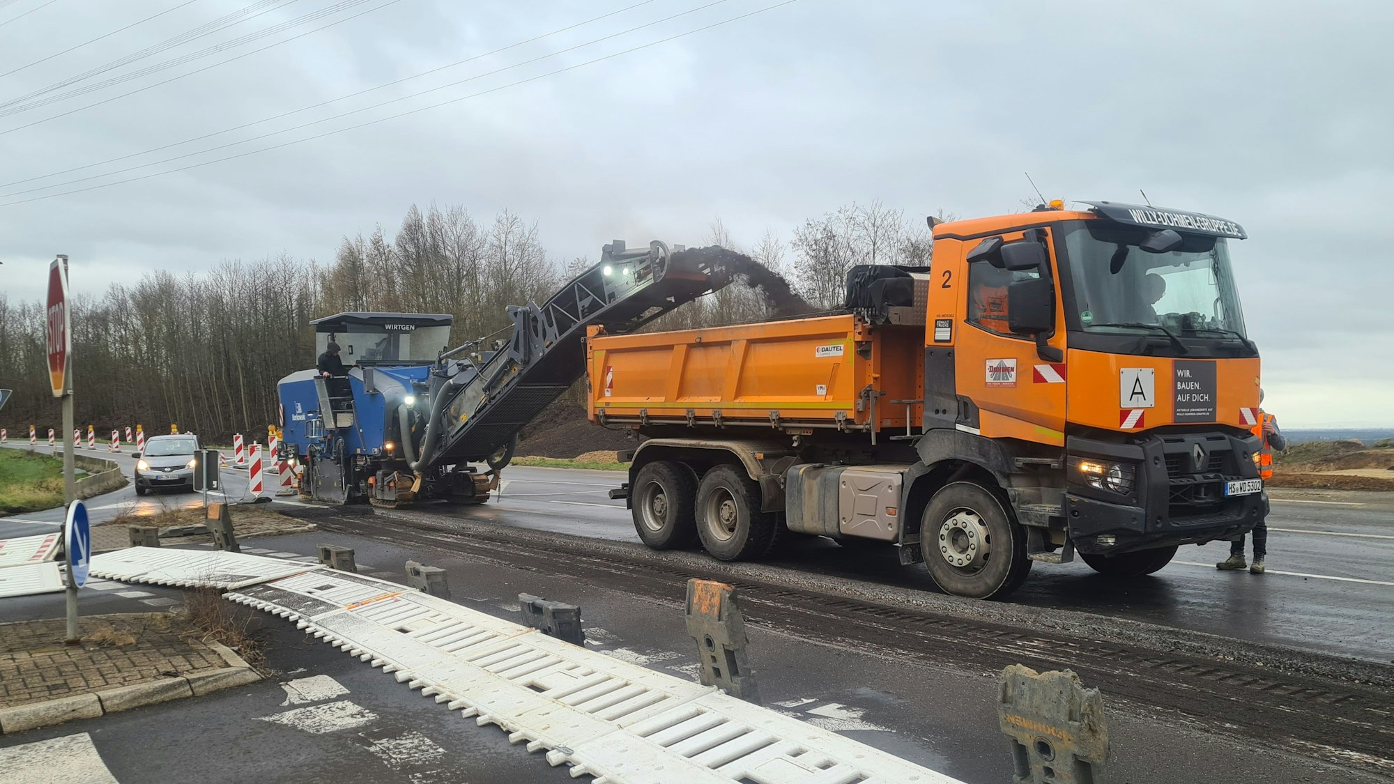 Auf dem Bild ist die Kreisstraße 22n zu sehen, befahren von zwei Baufahrzeugen.