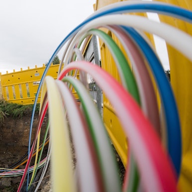 Leerrohre für Glasfaserleitungen für schnelles Internet liegen an einer Landstraße in der Baugrube.