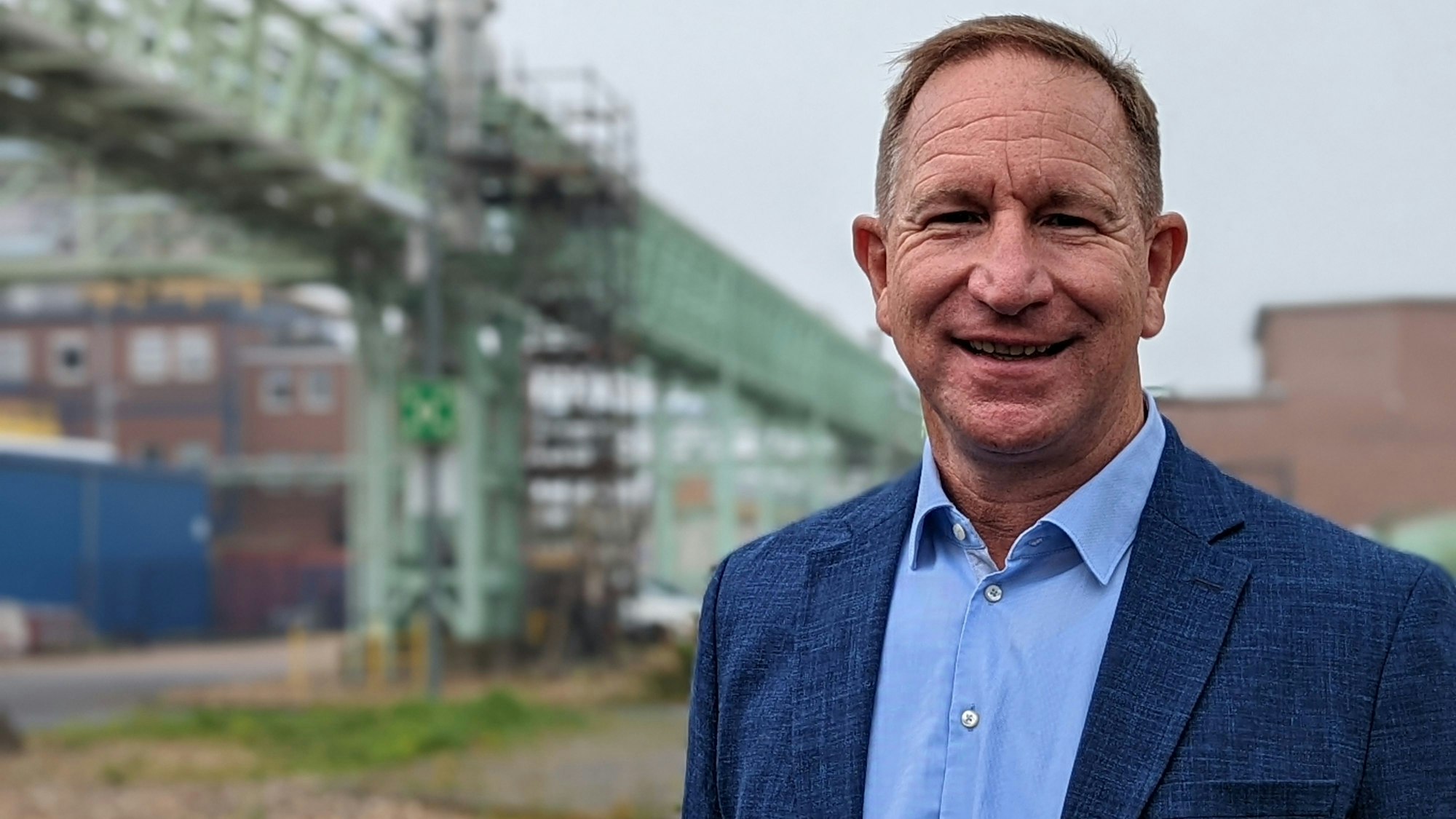 Das Foto zeigt Christoph Kappenhagen. Er ist Geschäftseiter von Yncoris im Chemiepark Knapsack. Im Hintergrund sind Werksanlagen zu sehen.