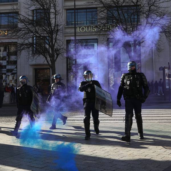 Frankreich, Paris: Polizisten gehen auf der Avenue des Champs-Elysees durch sich ausbreitendes Tränengas.