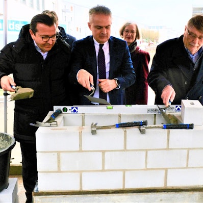 Grundsteinlegung mit weißen Steinen und Mörtel