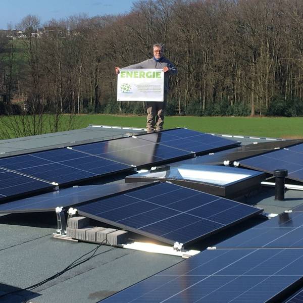 Stefan Häusler, Vorsitzender der Klimafreunde Rhein-Berg, steht auf einer Fotovoltaikanlage und hält ein Schild mit der Aufschrift „Energie“.