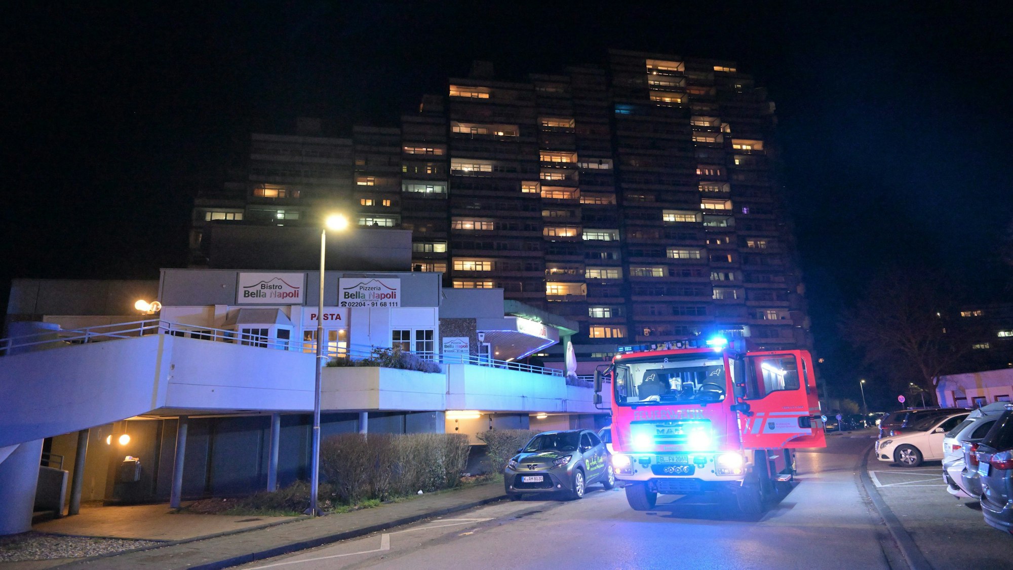 Ein Feuerwehrfahrzeug mit Blaulicht steht am Abend vor einem Hochhaus im Wohnpark Bockenberg bei Bergisch Gladbach-Bensberg.