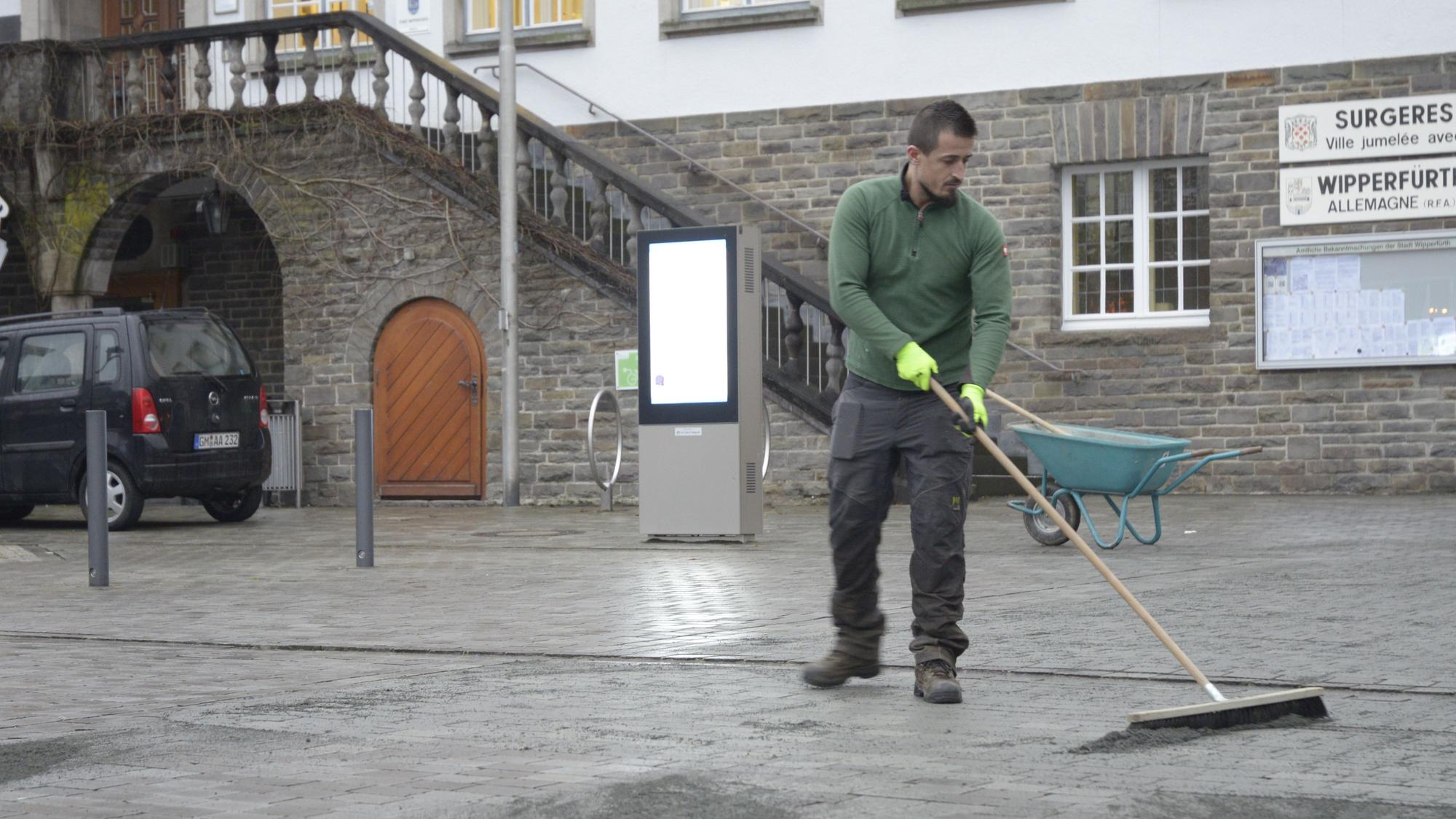 Ein Mitarbeiter der Firma G.W.D. verfugt die Grauwackesteine auf dem Marktplatz neu.