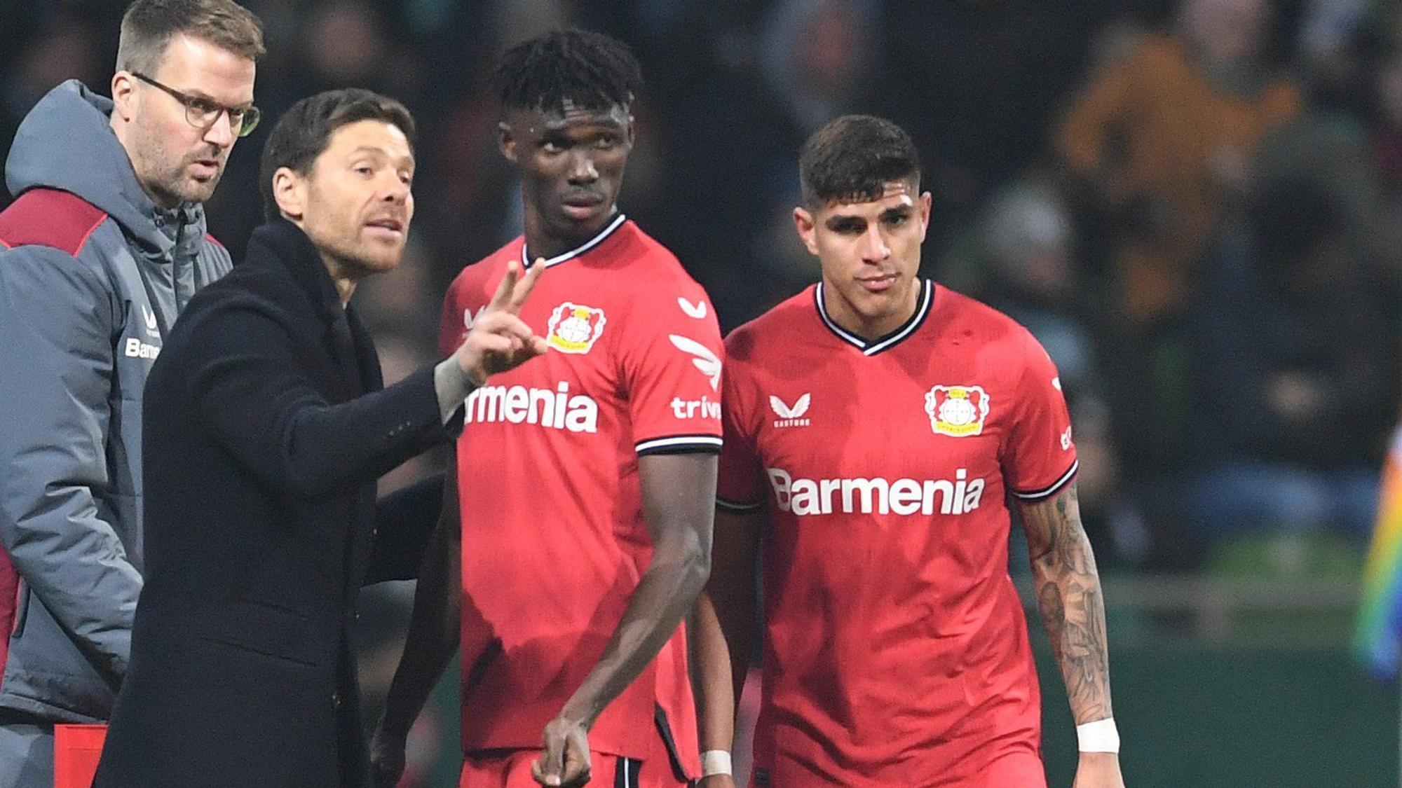 12.03.2023, Bremen: Fußball: Bundesliga, Werder Bremen - Bayer Leverkusen, 24. Spieltag, wohninvest Weserstadion. Leverkusens Trainer Xabi Alonso (l) spricht an der Seitenlinie mit Odilon Kossounou und Piero Hincapie (r). Foto: Carmen Jaspersen/dpa - WICHTIGER HINWEIS: Gemäß den Vorgaben der DFL Deutsche Fußball Liga bzw. des DFB Deutscher Fußball-Bund ist es untersagt, in dem Stadion und/oder vom Spiel angefertigte Fotoaufnahmen in Form von Sequenzbildern und/oder videoähnlichen Fotostrecken zu verwerten bzw. verwerten zu lassen. +++ dpa-Bildfunk +++