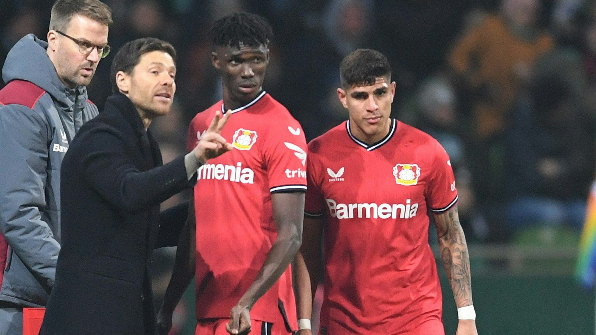 12.03.2023, Bremen: Fußball: Bundesliga, Werder Bremen - Bayer Leverkusen, 24. Spieltag, wohninvest Weserstadion. Leverkusens Trainer Xabi Alonso (l) spricht an der Seitenlinie mit Odilon Kossounou und Piero Hincapie (r). Foto: Carmen Jaspersen/dpa - WICHTIGER HINWEIS: Gemäß den Vorgaben der DFL Deutsche Fußball Liga bzw. des DFB Deutscher Fußball-Bund ist es untersagt, in dem Stadion und/oder vom Spiel angefertigte Fotoaufnahmen in Form von Sequenzbildern und/oder videoähnlichen Fotostrecken zu verwerten bzw. verwerten zu lassen. +++ dpa-Bildfunk +++