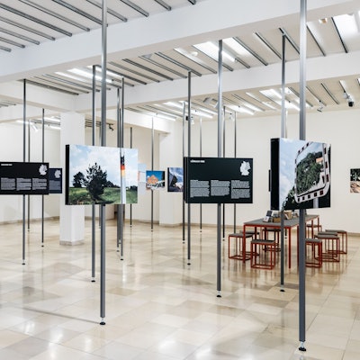 Ansicht der neuen Austellung im NS-DOK. Fotografien sind an Metallsäulen befestigt und willkürlich im Raum verteilt.